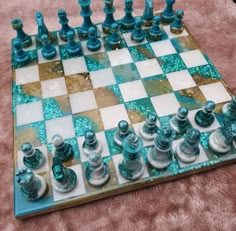 a blue and white chess set on top of a pink blanket with gold flecks