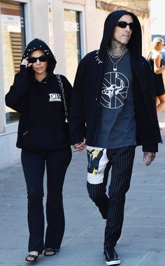 a man and woman walking down the street holding hands while wearing matching hoodie sweatshirts