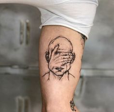 a man's arm with a drawing of a person covering his eyes and hands