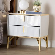 a white and gold nightstand with a potted plant on top