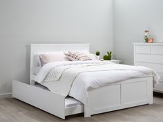 a white bed sitting in a bedroom on top of a hard wood floor next to a dresser