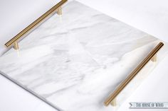 a marble serving tray with gold handles and two chopsticks on the side, sitting on a white surface