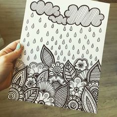 someone holding up a coloring book with an image of rain and clouds in the background