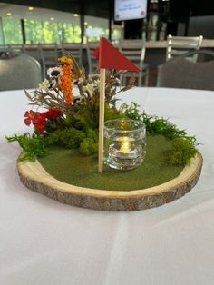 a table with a candle and some flowers on it, in the shape of a golf hole