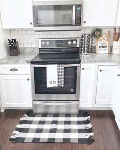 a kitchen with white cabinets and black and white checkered rugs on the floor