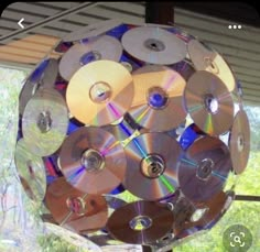 a bunch of cds that are hanging from a rack on a window sill in front of some trees