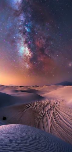 the night sky is filled with stars and bright lights above sand dunes in the desert