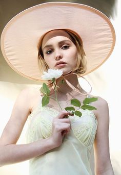 a woman wearing a pink hat and holding a flower