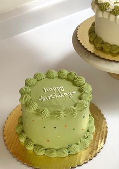 two birthday cakes with green frosting and white frosting on them, one has a happy birthday sign