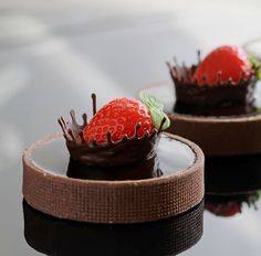 two chocolate covered desserts with strawberries on top