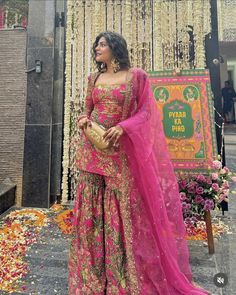 a woman in a pink and gold outfit standing next to a sign with flowers on it