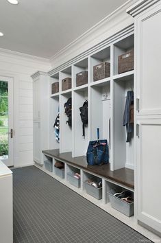 an organized mudroom with white cabinets and shelves filled with shoes, bags and purses