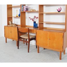 a wooden desk with two chairs next to it and a bookcase on the wall