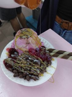 an ice cream sundae on a paper plate with cherries and chocolate beans in it