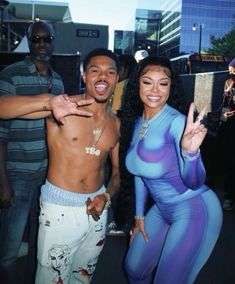 a man and woman in bodysuits posing for the camera with one hand up