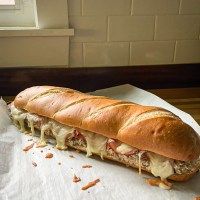 a sub sandwich sitting on top of a piece of wax paper next to a window