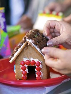 someone decorating a gingerbread house on a plate