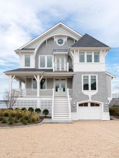 a large gray and white house sitting on top of a sandy beach