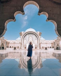 a person standing in front of a large building with arches and columns on the sides