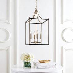 a white table with books and flowers on it next to a chandelier hanging from the ceiling