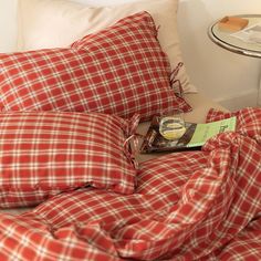 a red and white checkered comforter on top of a bed next to a night stand