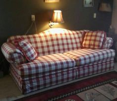 a red and white checkered couch sitting in a living room next to a lamp