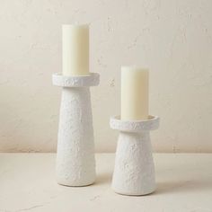 two white candles sitting on top of each other