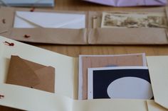 an open book with paper and pictures on the pages, sitting on top of a wooden table