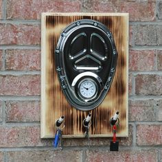 a clock mounted to the side of a brick wall next to two hooks with keys