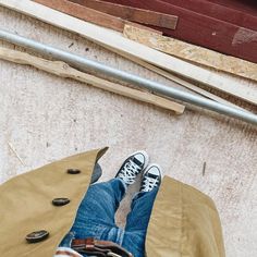 a person sitting on the ground with their feet propped up in front of some wood planks