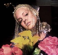 a woman with long blonde hair holding flowers in front of her face