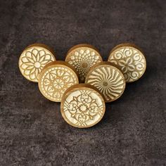 six wooden buttons with intricate designs on them sitting on a surface in front of a dark background