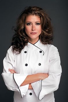 a woman wearing a chef's coat and posing for a photo with her arms crossed