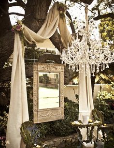 a chandelier hanging from a tree next to a mirror