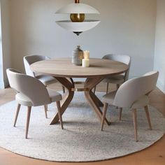 a round table with four chairs around it in a room that has white walls and wood floors