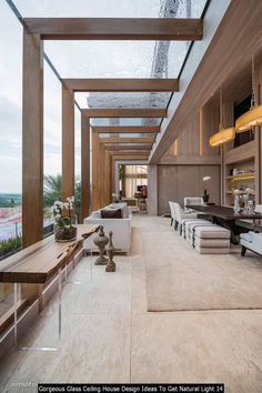 a large living room filled with lots of furniture next to a tall glass window covered ceiling