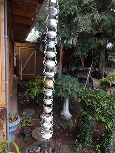 a metal chain hanging from the side of a building with pots and plants in it