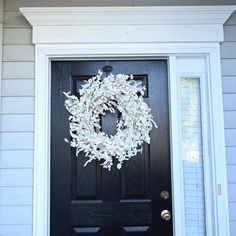 a black front door with a white wreath on it