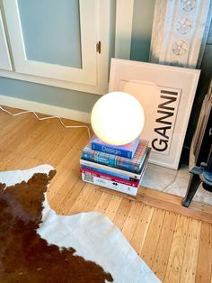 a lamp sitting on top of a pile of books next to a cowhide rug