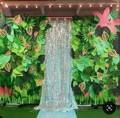 a stage set up for a party with green and pink decorations on the wall behind it