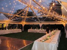 a large tent with tables and chairs set up for a wedding reception in the evening