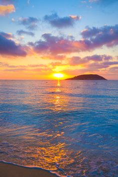 the sun is setting over the ocean with small islands in the distance and waves coming in