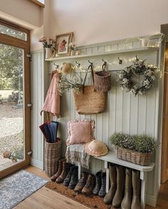 the entryway is decorated with baskets, umbrellas, and boots on display next to an open door