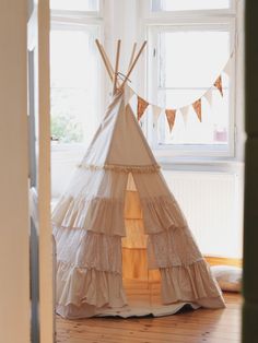 a teepee tent sitting on top of a wooden floor in front of a window