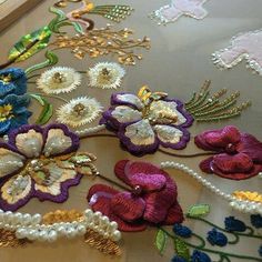 a table topped with lots of different types of embroidered flowers and pearls on top of it