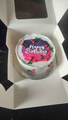 a birthday cake in a white box with pink frosting and flowers on the side