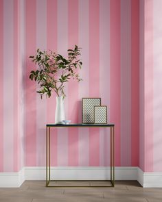 a pink and white striped wallpapered room with a vase filled with flowers on a table