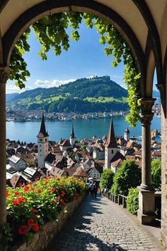 an archway leading to the city with flowers in front of it and mountains in the background