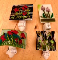 four glass coasters with flowers on them sitting on a wooden table next to each other