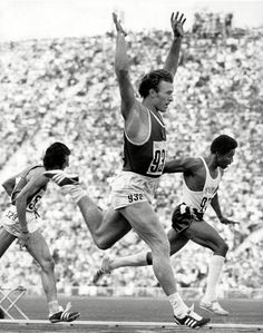 two men running on a track in front of an audience